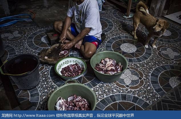 One worker is seen chopping up pieces of meat in preparation for it to be cooked in a cafe