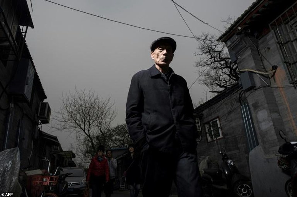 An elderly resident walks in a typical hutong alleyway.  Hundreds of years ago the lane would be lined with stately red doors which led to spacious courtyards decorated with carved roof beams and painted pillars