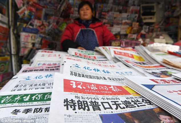 A newsstand vendor stands behind newspapers including one with a  story (foreground) about Donald Trump that reads: 'Trump's inability to keep his mouth shut is stunning'