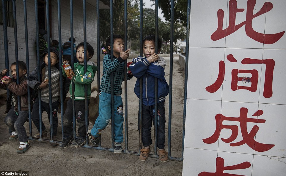 A group of children stand at the gates to a local school in Anshun where millions of Chinese children are left behind as their parents go to work in the cities