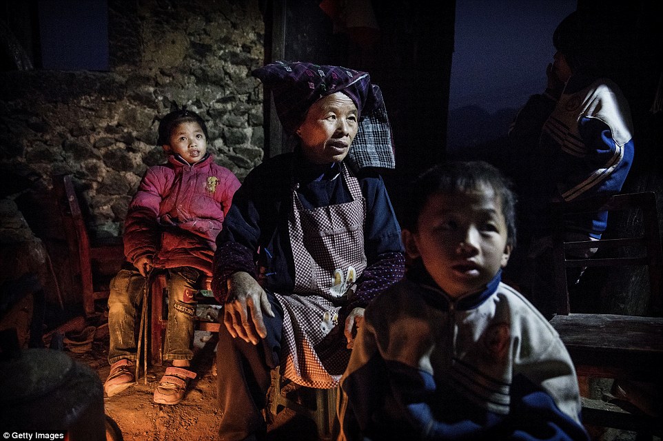 Siblings Luo Lie five (right) and sister Luo Hongniu eight with grandmother Lu Guoxiu 64 sit around a cooking fire to stay warm