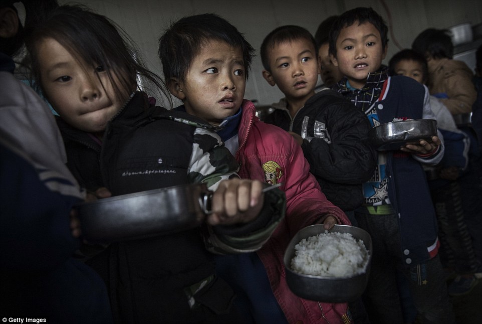 Groups of children queue with containers of rice. Like millions across China they rarely see their parents who are away working in urban areas