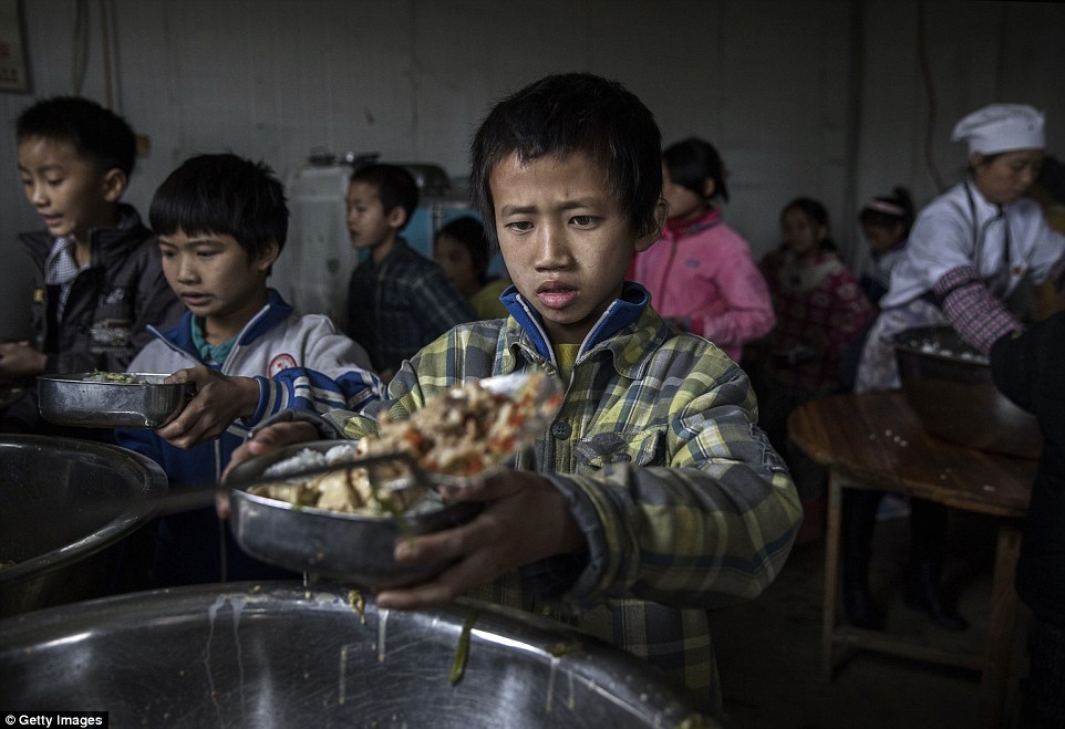 Luo Gan aged 10 is served lunch at a local school. He is one of an estimated 61 million children whose parents work in urban areas