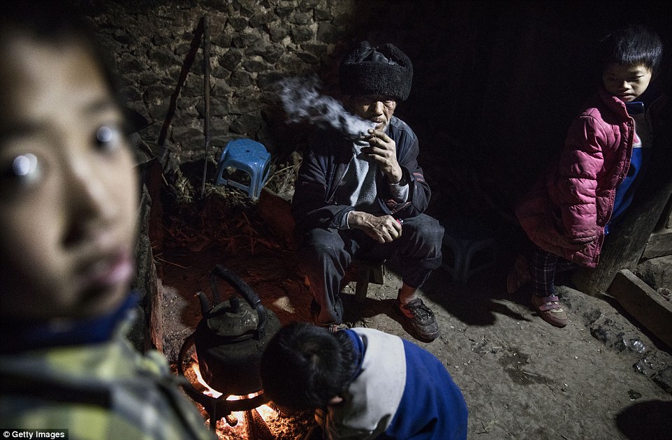 Grandfather Luo Yingtao 64 sits with his grandchildren Luo Gan 10 and Luo Hongniu 8 right who are 'left behind' at the family house