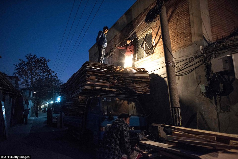 Workers collect cardboard boxes in a hutong. Hutong residents have the habit of recycling used goods from furniture to glass bottles by selling them to rubbish collectors