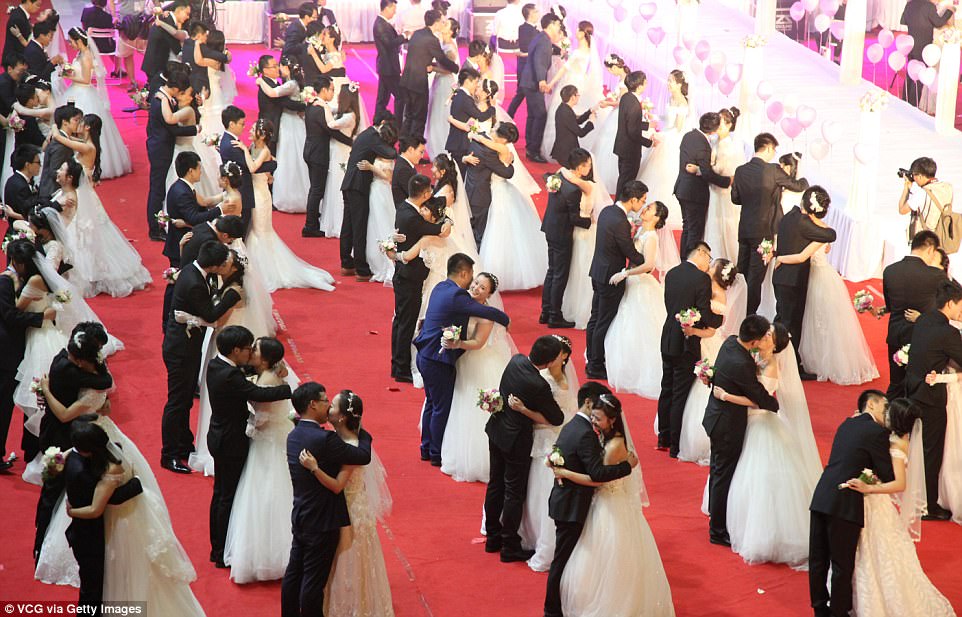 A hug and a kiss: The sea of white bridal dresses and well-tailored grooms comprised 57 alumni couples 6 staff couples and 52 student pairs