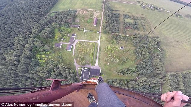 Risking his life: The daredevil dangles over the edge of the enormous structure while celebrating his ascent